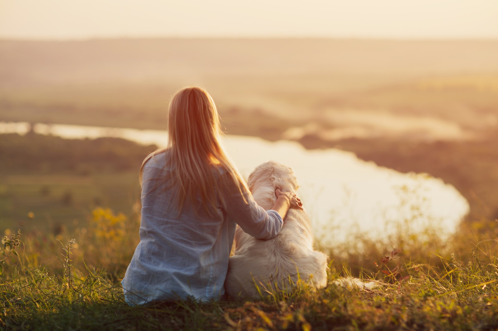 Woman sitting with her dog watching the sunset